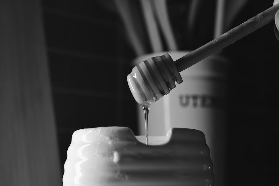 Miel qui coule d'un pot en verre posé sur une table