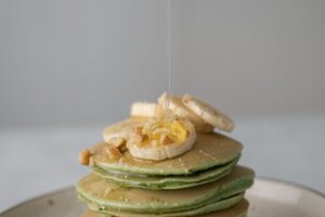 Pile de pancakes nappés de miel et tranches de banane